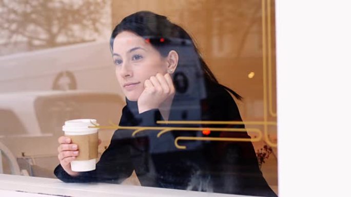 女人边喝咖啡边透过窗户看