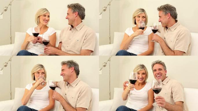 成熟的夫妇在沙发上一起喝红酒