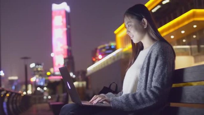 年轻的亚洲女性在现代城市玩笔记本电脑