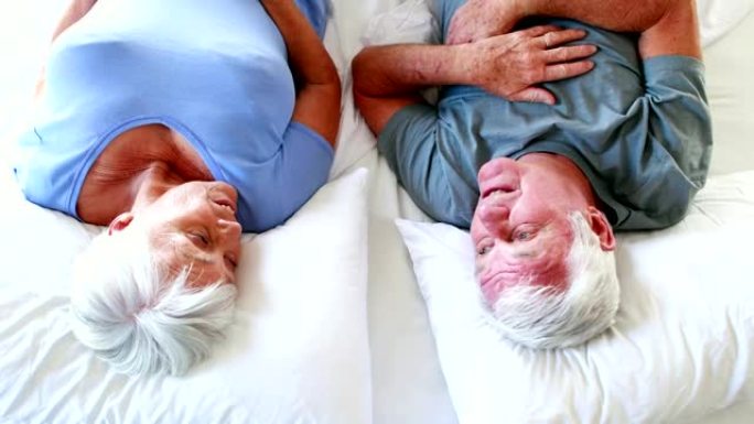 快乐的老年夫妇躺在床上