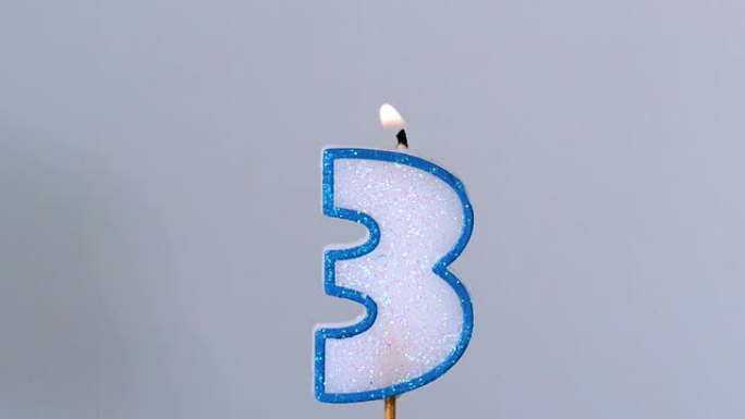 三根生日蜡烛在蓝色背景上闪烁和熄灭