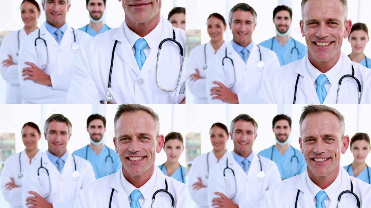 医生在镜头前微笑，团队在他身后