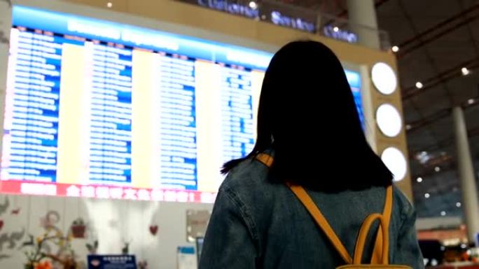 女旅客在机场看航班信息屏幕