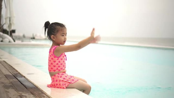 一个可爱的快乐的年轻女婴婴儿在游泳池边放松。