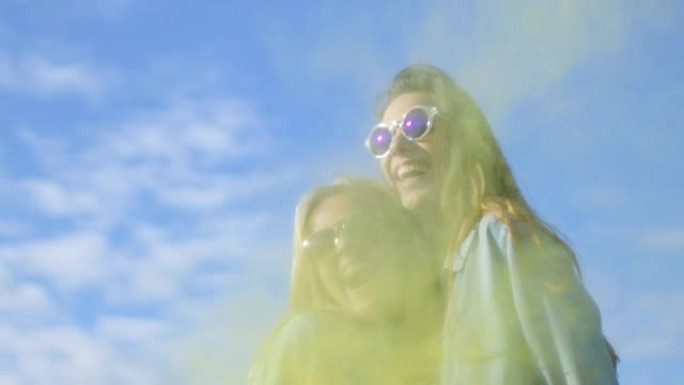 两个美丽快乐的女孩笑着庆祝胡里节五颜六色的粉末在她们背后飞舞。他们玩得很开心。