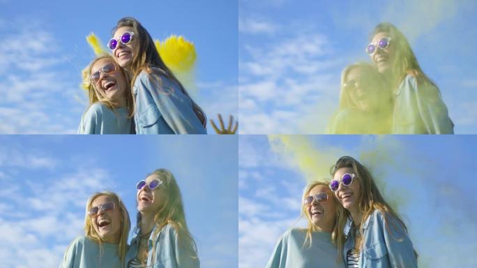 两个美丽快乐的女孩笑着庆祝胡里节五颜六色的粉末在她们背后飞舞。他们玩得很开心。