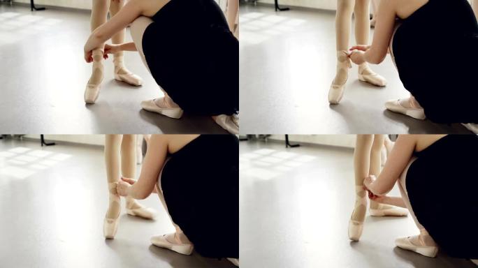 乐于助人的老师在芭蕾舞课前将脚尖鞋放在小学生的脚上，在小腿上系上丝带。舞蹈、鞋类和人的概念。
