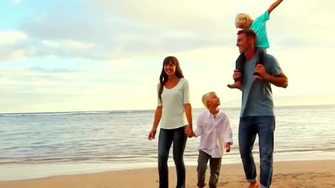 快乐的年轻高加索家庭走在沙滩上