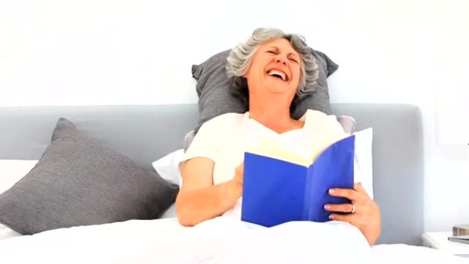 年长的女人在床上看书