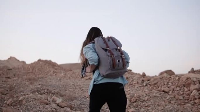 女人在陡峭的岩石山上徒步旅行。慢动作。旅游女孩用大石头爬山。艰难的登顶之路