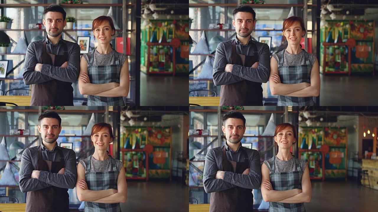 两个骄傲的小企业主站在新宽敞的咖啡馆里微笑的肖像。成功的创业，快乐的人和餐饮服务理念。