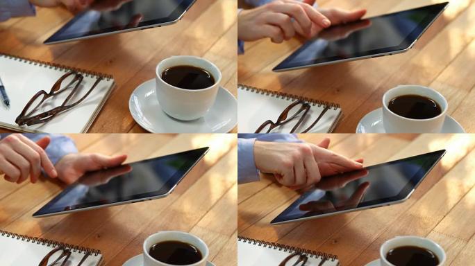 女商人在桌子上使用数字平板电脑，桌上放着一杯咖啡，眼镜和笔记本