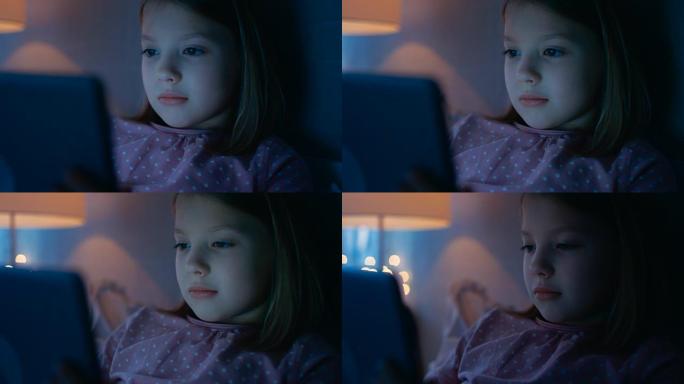 当她看着照亮她脸的平板电脑时，一个可爱的年轻女孩脸的特写镜头。