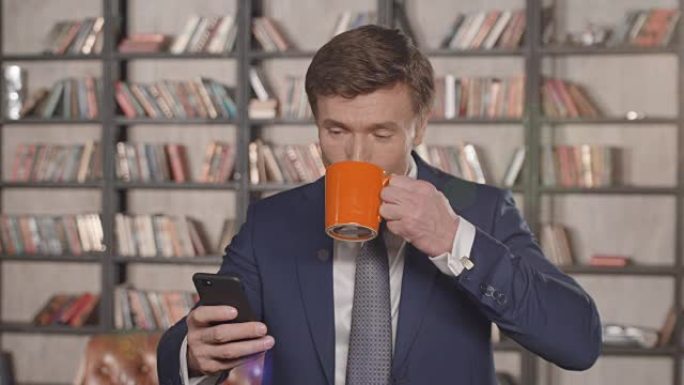 成功的有吸引力的商人在智能手机上输入消息并在办公室微笑着喝咖啡的慢动作肖像。商人系列。