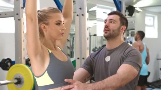 教练建议一名在健身房用哑铃锻炼的妇女