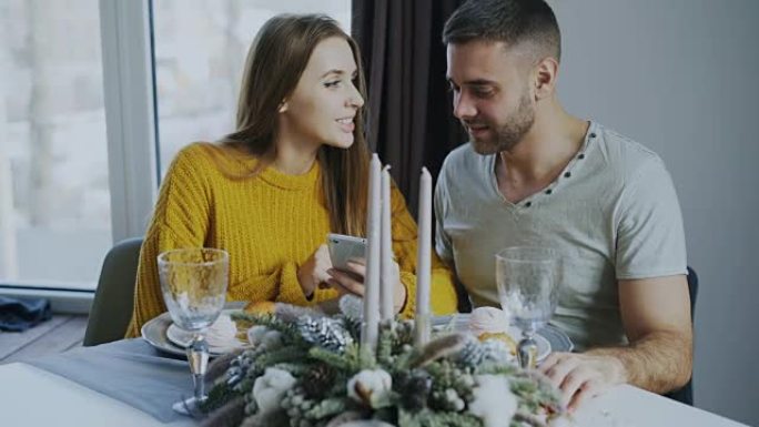 年轻的微笑夫妇在室内咖啡馆吃午餐时浏览智能手机