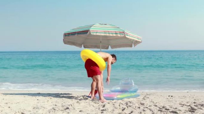 快乐的男人躺在沙滩上，带着橡胶圈
