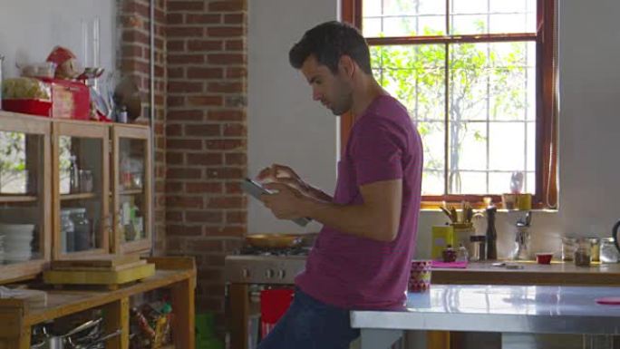 年轻人站在厨房里使用平板电脑，在R3D上拍摄