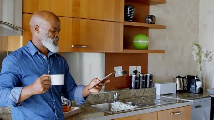 高级男子在4k厨房喝黑咖啡时使用数字平板电脑