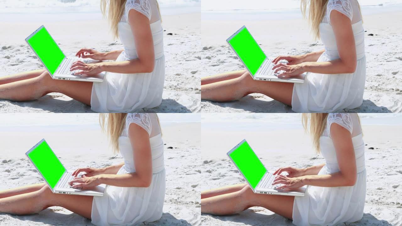 漂亮的金发女人在海滩上使用笔记本电脑