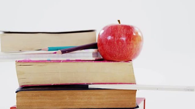 白色背景下的书籍、彩色铅笔和苹果