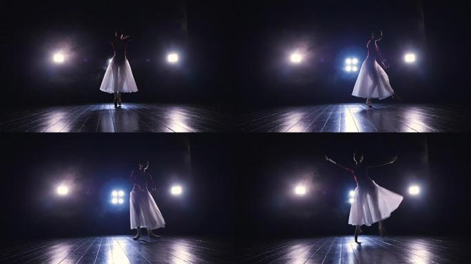 穿着飘逸长裙的孤独芭蕾舞演员在黑暗中表演。4K。