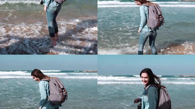 美丽的欧洲女孩在海边试水。美丽的女人对着镜头微笑。风吹进头发。慢动作