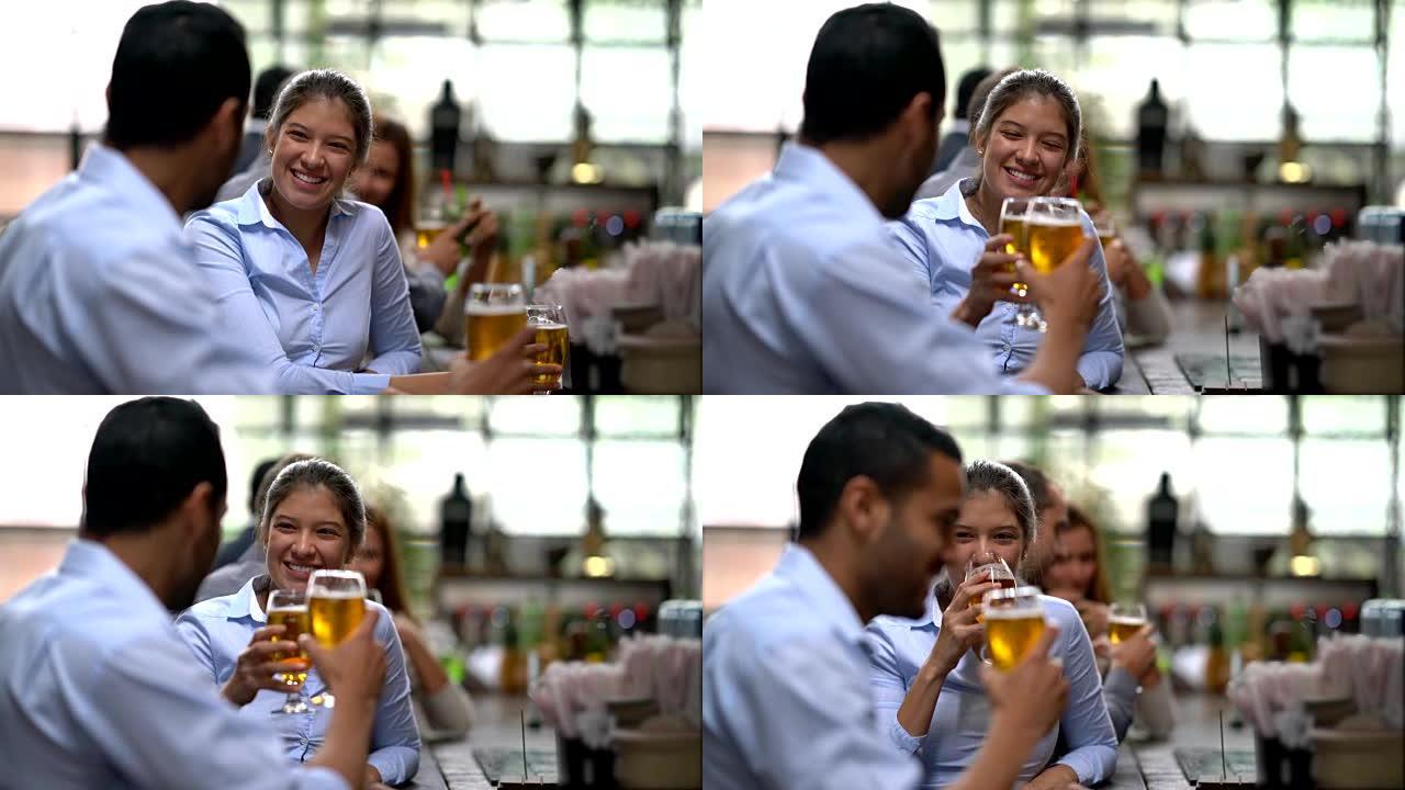 酒吧里的年轻夫妇享受着啤酒，在欢乐时光里敬酒