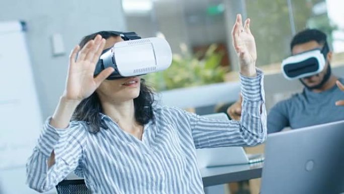 戴着虚拟现实耳机的女性虚拟现实工程师/开发人员与同事一起创建内容。富有创造力的年轻人从事增强和混合现