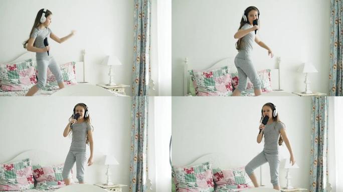 有趣可爱的小女孩戴着无线耳机，用梳子跳舞，在舒适的卧室里的床上玩得开心