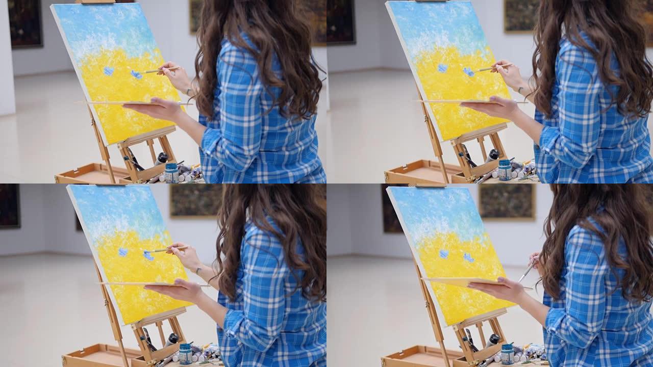 女孩用蓝色画一幅画。