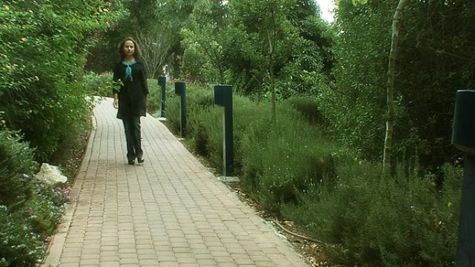 一名妇女在公园的人行道上行走