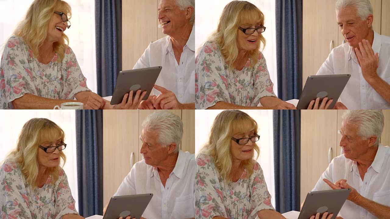 快乐的高级夫妇看着数字平板电脑讨论