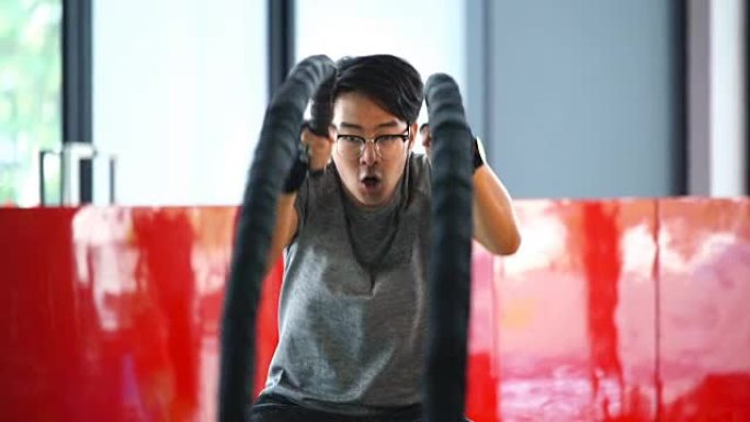 SLO MO-亚洲男子用战斗绳锻炼的特写镜头