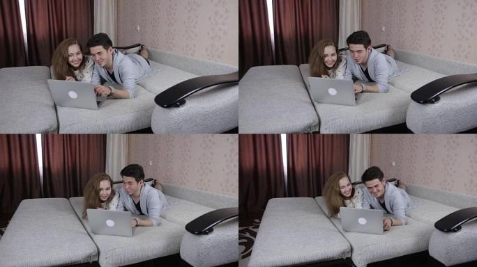 微笑的夫妇在家里用笔记本电脑。技术、家庭概念