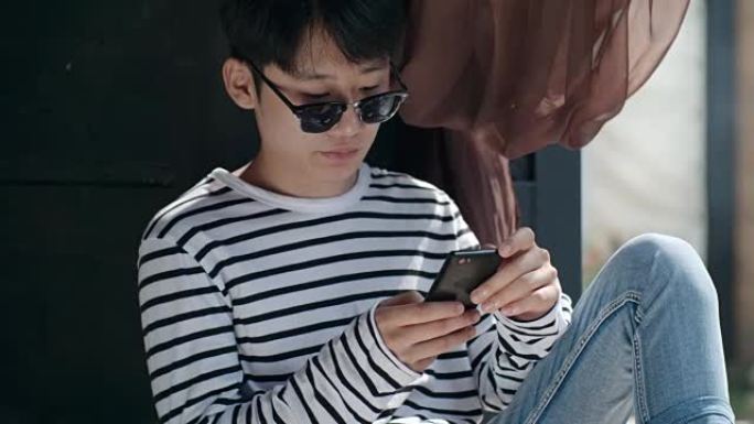 亚洲男孩在户外露台上使用智能手机