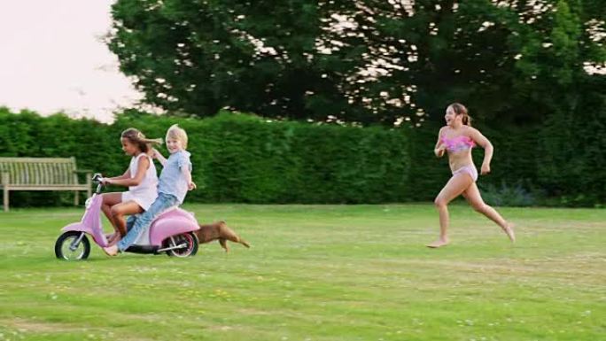十几岁的孩子在花园里和滑板车和狗玩得开心