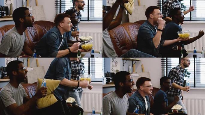 非裔美国朋友在电视上观看体育节目。慢动作。球迷们用爆米花在沙发上兴奋地庆祝进球。情感