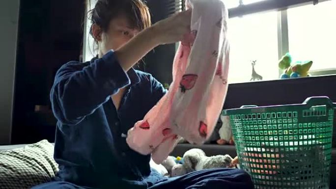 亚洲女人在床上折叠衣物。