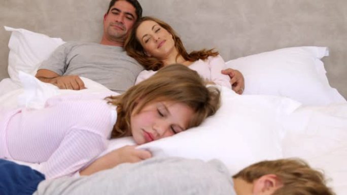 可爱的父母和孩子躺在床上睡觉