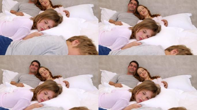 可爱的父母和孩子躺在床上睡觉