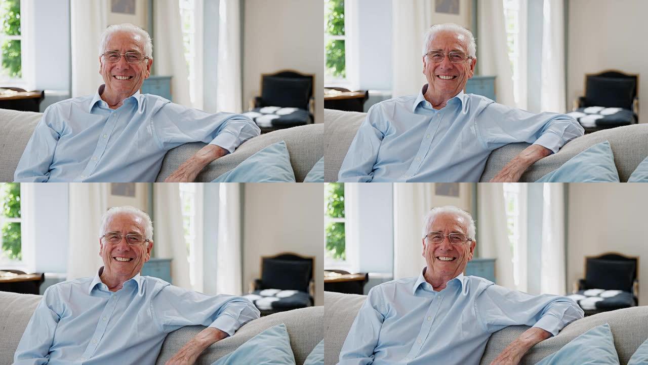 微笑的老人坐在家里的沙发上的肖像