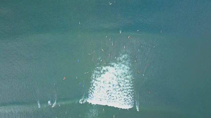 空中: 生动的冲浪板上的人群同时骑着泡沫波