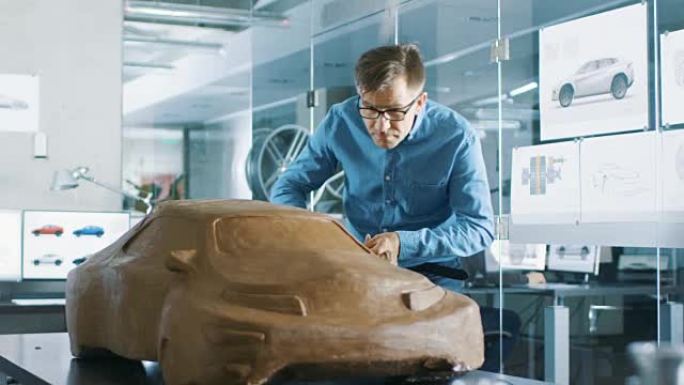 体验汽车设计师用橡皮泥雕刻原型汽车模型。他在一家大型汽车公司总部的现代工作室工作。