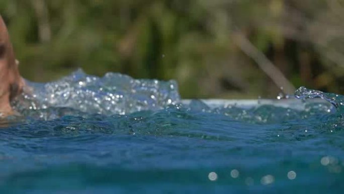 慢动作女人的手滑过水面，在游泳池里溅起水滴