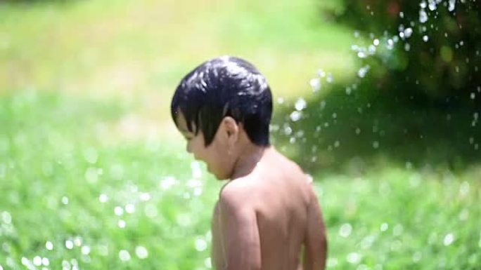 SLO MO蹒跚学步的孩子在家里的前院玩水。