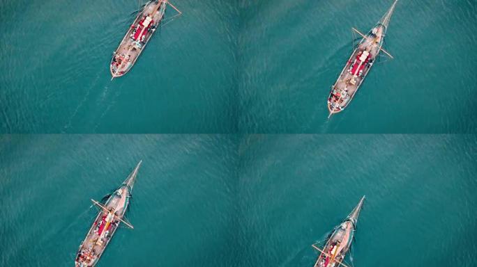 一架无人机从海上一艘帆船的桅杆上方飞过。
