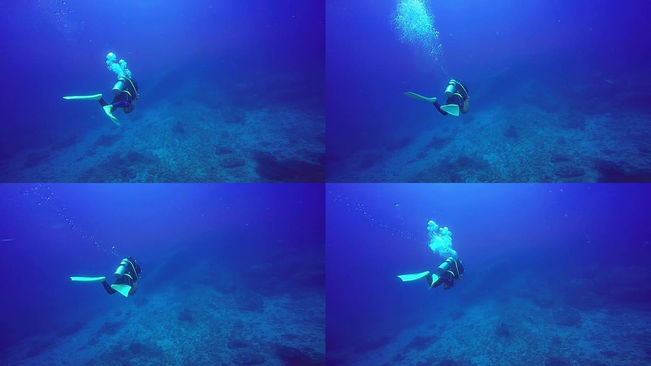 水肺潜水员在蓝色清澈的水中游泳的水下拍摄。