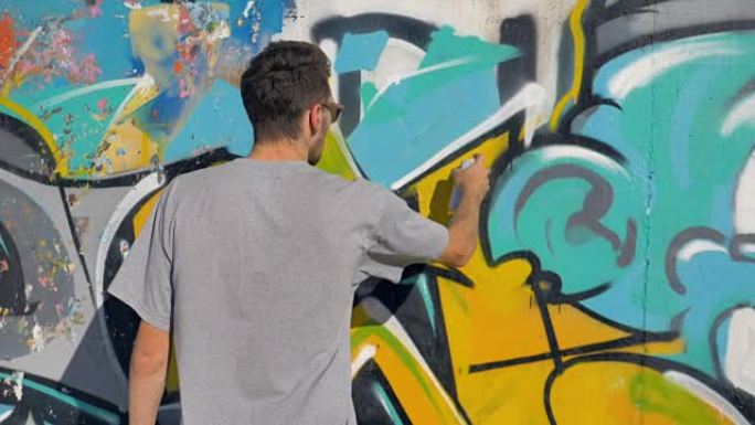 艺术家正在墙上画一个黄色的字母，特写。