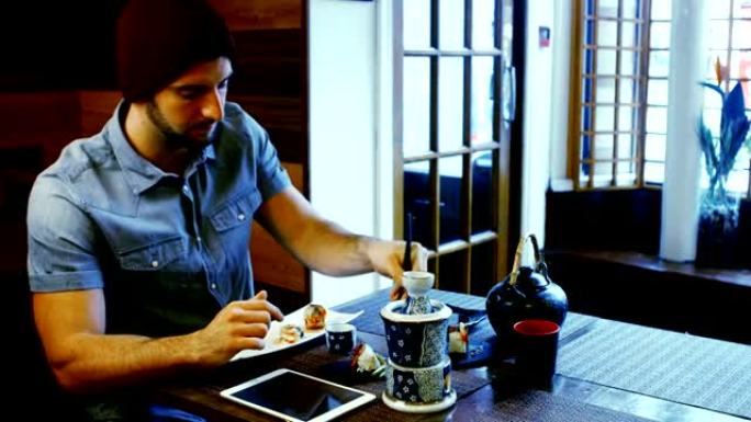 男人在吃寿司时使用数字平板电脑
